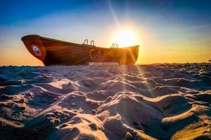 A wooden boat on the beach that says Cape May on